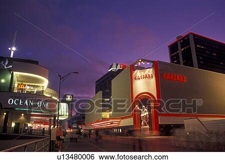 Stock Photograph -  casino, Atlantic City, boardwalk, Caesars, New Jersey, Caesars Casino Hotel on the boardwalk in Atlantic City illuminated at night in the state of New Jersey. . Fotosearch