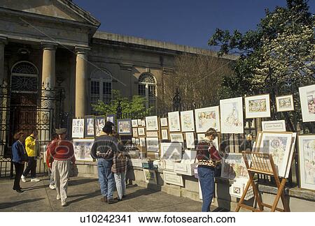 Stock Image -  Charleston, South Carolina, street art, Tourists walk by displays of artwork for sale on fence in front of St. Philip's Episcopal Church in Charleston in the state of South Carolina. . Fotosearch