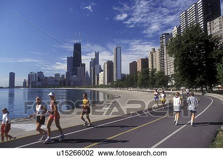 Chicago, Illinois, People jog on the recreation path on the waterfront of Lake Michigan. The skyline of downtown Chicago towers above in the background View Large Photo Image Stock Image - Chicago, Illinois, People jog on the recreation path on the waterfront of Lake Michigan. The skyline of downtown Chicago towers above in the background . Fotosearch