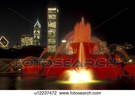 Chicago, Illinois, The Buckingham Memorial Fountain at Grant Park is illuminated at night by red lights. The illuminated skyline of downtown Chicago towers in the background., View Large Photo Image Stock Image - Chicago, Illinois, The Buckingham Memorial Fountain at Grant Park is illuminated at night by red lights. The illuminated skyline of downtown Chicago towers in the background., . Fotosearch