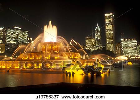 Chicago, Illinois, The Buckingham Memorial Fountain at Grant Park is illuminated at night. The illuminated skyline of downtown Chicago towers in the background., View Large Photo Image Stock Photo - Chicago, Illinois, The Buckingham Memorial Fountain at Grant Park is illuminated at night. The illuminated skyline of downtown Chicago towers in the background., . Fotosearch
