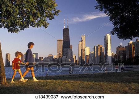 Stock Photo -  Chicago, skyline, Illinois, Skyline of downtown Chicago from Lincoln Park on Lake Michigan in the state of Illinois. Mother and daughter walking along the waterfront.. Fotosearch