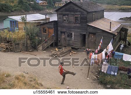 Stock Image -  Chili, Chiloe Island, Boys playing soccer in front of his house with laundry hanging in the yard on Chiloe Island in Chile . Fotosearch