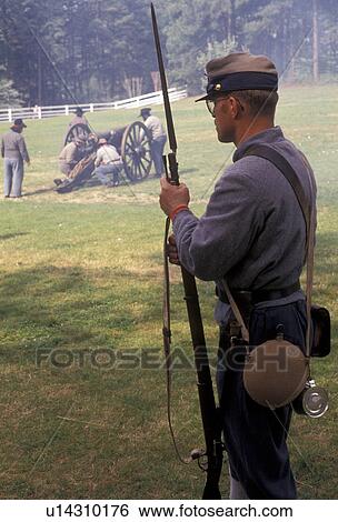 Stock Photograph -  Civil War Reenactment, Confederate soldier, Confederate, Stone Mountain, Atlanta, Georgia's Stone Mountain Park, Georgia, Man dressed as Confederate Soldier looks on as men load cannon during the Civil War Reenactment at the Antebellum Jubilee at Stone M. Fotosearch