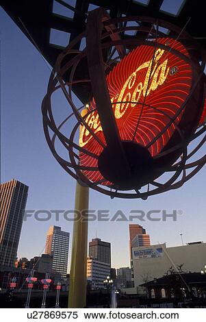 Stock Photography -  Coca Cola, Atlanta, Georgia, Underground Atlanta, The red Coke sign at the World of Coca-Cola is illuminated in the evening. Downtown skyline of Atlanta in background.. Fotosearch