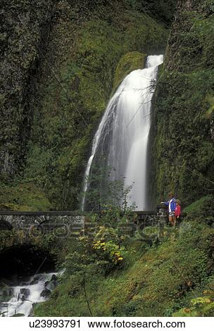 Stock Image -  Columbia River Gorge, cascade, waterfall, Columbia River, Oregon, Mt. Hood National Forest, Mother and daughter stand looking at Wahkeena Falls at the Columbia River Gorge National Scenic Area in the state of Oregon.. Fotosearch