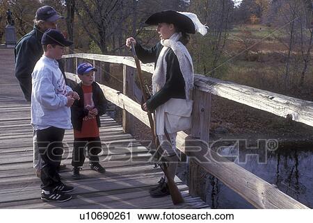 Stock Image -  Concord, Massachusetts, A Minute Man Interpreter demonstrates to tourists The Smoothbore Musket on the North Bridge at the Minute Man National Historic Site., . Fotosearch