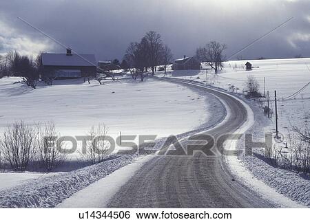 Stock Photograph -  country road, winter, Vermont, A country road winds through the scenic snow covered countryside in winter with storm clouds in the distance in East Montpelier in Washington County in the state of Vermont.. Fotosearch