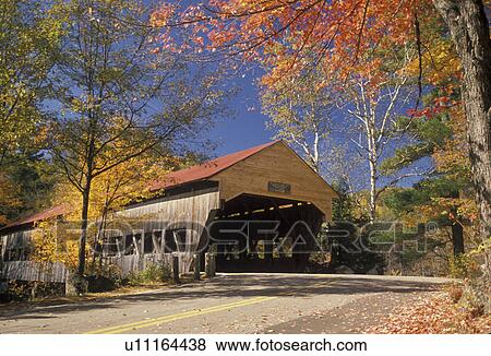 Stock Photo -  covered bridge, New Hampshire, White Mountains, fall, A covered bridge with a red roof is surrounded by colorful fall foliage on a beautiful autumn day in the White Mountain National Forest. . Fotosearch