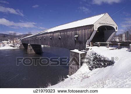 Stock Image -  covered bridge, Vermont/New Hampshire, VT/NH, Windsor-Cornish Covered Bridge crosses over the Connecticut River in the snow in winter. . Fotosearch