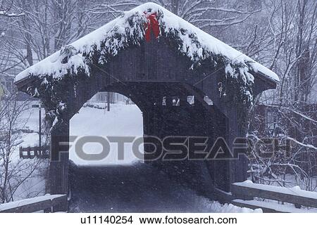 Picture -  covered bridge, winter scene, Vermont, Christmas decorations on the snow covered Village or Church Street Covered Bridge on a winter day in Waterville in Lamoille County in the state of Vermont. . Fotosearch