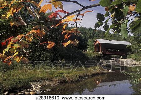 Stock Image -  covered bridge, wooden bridge, fall, Vermont, Colorful maple leaves frame the Upper Covered Bridge which crosses the Cox Brook in Northfield Falls in Washington County in the state of Vermont during the autumn season.. Fotosearch