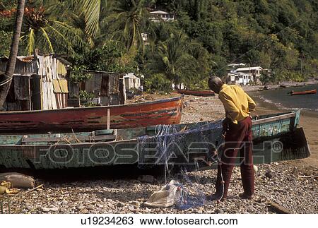 Stock Image -  Dominica, Caribbean, Caribbean Islands, Local fishermen working with fishing nets on the beach in Soufriere on the island of Dominica.. Fotosearch