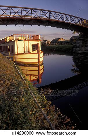 Erie Canal, barge, New York, A canal barge reflects in the calm water of the Erie Canal in the early morning light at the Erie Canal Village in Rome in the state of New York. View Large Photo Image Stock Image - Erie Canal, barge, New York, A canal barge reflects in the calm water of the Erie Canal in the early morning light at the Erie Canal Village in Rome in the state of New York.. Fotosearch
