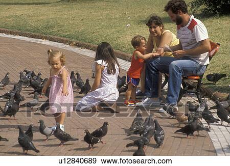 family, Buenos Aires, Argentina, A mother and father with three children are feeding pigeons in the park in the capital city of Buenos Aires. The parents are sitting on a bench. View Large Photo Image Stock Photo - family, Buenos Aires, Argentina, A mother and father with three children are feeding pigeons in the park in the capital city of Buenos Aires. The parents are sitting on a bench.. Fotosearch