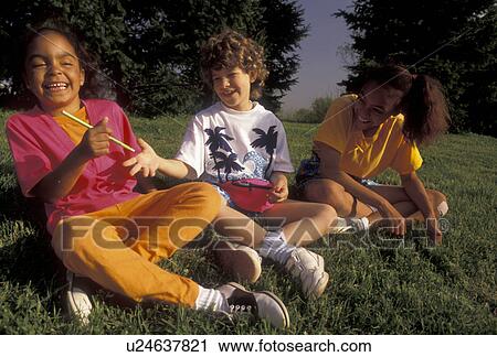 friendship, multi-ethnic, girls, friend, Two (black, African-American) girls and one (white, Caucasian) girl sit together playing and laughing on a grassy hill on a warm spring day in Exton in the state of Pennsylvania. The white girl is in between the t View Large Photo Image Stock Image - friendship, multi-ethnic, girls, friend, Two (black, African-American) girls and one (white, Caucasian) girl sit together playing and laughing on a grassy hill on a warm spring day in Exton in the state of Pennsylvania. The white girl is in between the t. Fotosearch