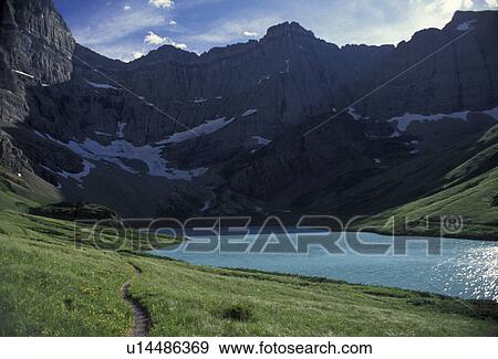 Glacier National Park, glacier lake, mountains, trail, Montana, Waterton-Glacier International Peace Park, A hiking trail passes along Cracker Lake with mountains in the background. View Large Photo Image Stock Photo - Glacier National Park, glacier lake, mountains, trail, Montana, Waterton-Glacier International Peace Park, A hiking trail passes along Cracker Lake with mountains in the background.. Fotosearch