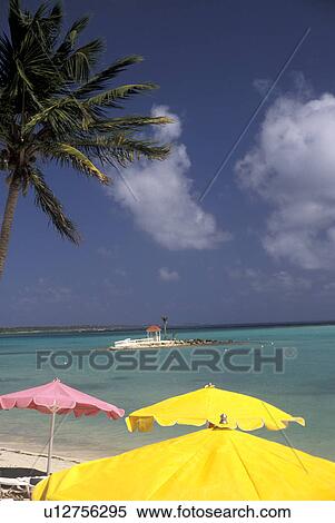 Stock Photography -  Guadeloupe, Caribbean, resort, Caribbean Islands, Scenic view of the blue-green water of the Caribbean Sea from the shoreline with yellow and pink beach umbrellas at Hotel Meridien in St. Francois on the island of Grande-Terre in Guadeloupe (a french dep. Fotosearch