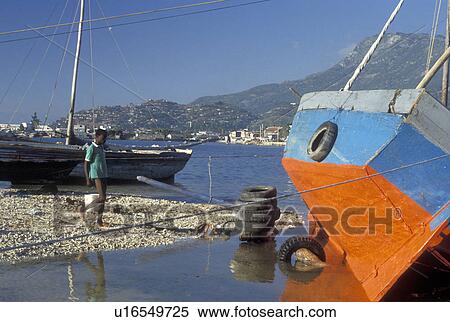 Stock Photography -  Haiti, Caribbean, Red & blue fishing boat beached at low tide on the Atlantic Ocean in Cap-Haitian Harbor in Haiti . Fotosearch