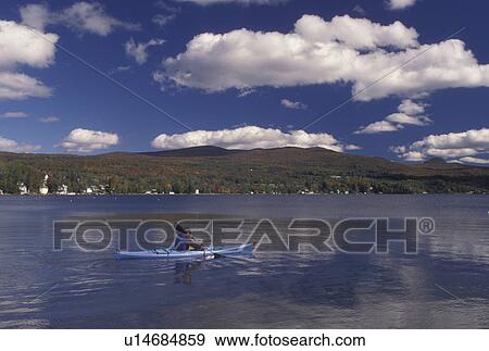 kayak, lake, Vermont, A man paddles his blue kayak on the calm waters of Lake Willoughby on a beautiful sunny day with blue sky and puffy white clouds above in Westmore in Orleans County in the state of Vermont. View Large Photo Image Stock Photo - kayak, lake, Vermont, A man paddles his blue kayak on the calm waters of Lake Willoughby on a beautiful sunny day with blue sky and puffy white clouds above in Westmore in Orleans County in the state of Vermont. . Fotosearch