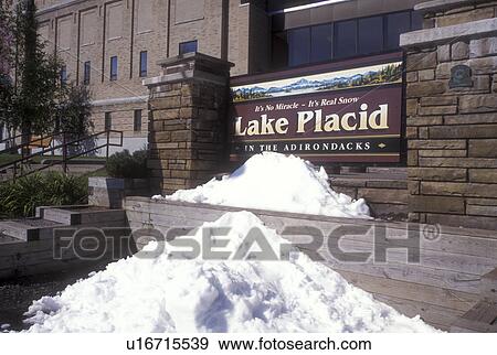 Stock Photo -  Lake Placid, Adirondacks, Adirondack Park, New York, Olympic Center in Lake Placid in the state of New York. Snow in front of sign in summer.. Fotosearch