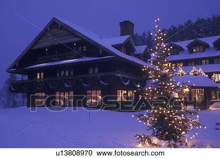 Stock Image -  lodge, inn, Trapp Family Lodge, winter, Vermont, Christmas, X-mas, Xmas, The snow covered Trapp Family Lodge is decorated with lights in the evening for the Christmas holiday season in Stowe in Lamoille County in the state of Vermont. A evergreen tree is. Fotosearch