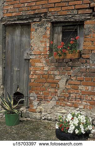 Stock Photo -  Lorraine, France, Europe, Moselle, Old worn brick and mortar wall with an old wooden door is decorated with flowers in Fribourg.. Fotosearch