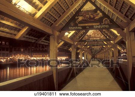 Stock Image -  Lucerne, Switzerland, covered bridge, Luzern, Europe, There are more than 100 gable paintings on the interior of the 14th century covered pedestrian bridge, the Kapellbrucke, on the Reuss in the evening in Lucerne in the Canton of Lucerne. . Fotosearch