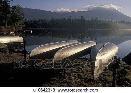 Stock Photo -  Maine, canoe, lake, reflection, Baxter State Park, Mt. Katahdin, Canoes rest on racks in the early morning on the calm waters of Daicey Pond in Baxter State Park. Mt. Katahdin reflects in the quiet misty water.. Fotosearch