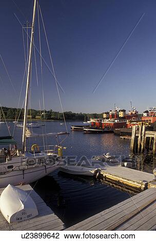 Stock Image -  Maine, harbor, Atlantic Ocean, Sailboat and fireboats moored at the docks on the harbor in Belfast in the state of Maine.. Fotosearch