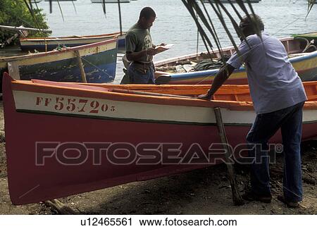 Stock Image -  Martinique, Caribbean, Caribbean Islands, Local fisherman working on a red fishing boat on the beach in Le Marin on the island of Martinique (a french department).. Fotosearch