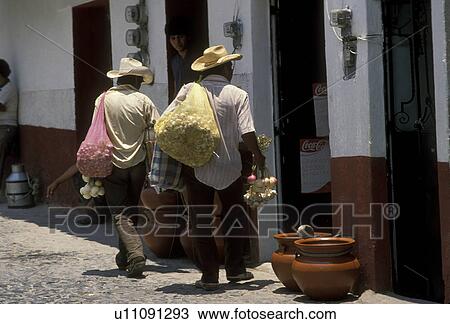Stock Image -  Mexico, Taxco, Mexican men carrying large bags of goods and selling door to door in the town of Taxco Silver City in the state of Guerrero. Taxco is the oldest mining town in North America . Fotosearch
