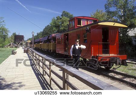 Stock Photography -  Michigan, train, Flint, A train conductor stands in front of the red caboose waiting for passengers at the Crossroads Village & Huckleberry Railroad in Flint.. Fotosearch