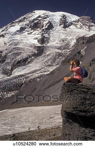 Mount Rainier, Mt. Rainier National Park, Cascades, Cascade Range, Washington, A woman hiker sits on a boulder looking through binoculars at the scenic view of the snow covered Mt. Rainier from Wonderland Trail in the Cascade Mountain Range in Mount Rain View Large Photo Image Stock Image - Mount Rainier, Mt. Rainier National Park, Cascades, Cascade Range, Washington, A woman hiker sits on a boulder looking through binoculars at the scenic view of the snow covered Mt. Rainier from Wonderland Trail in the Cascade Mountain Range in Mount Rain. Fotosearch