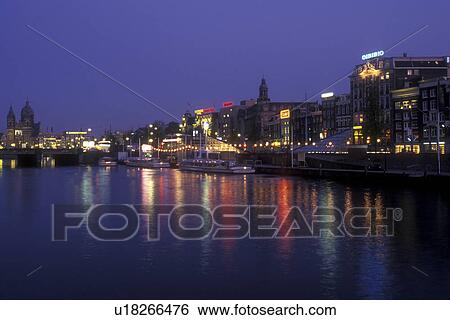 Netherlands, Amsterdam, The lights of Open Haven Front in downtown Amsterdam reflect in the calm waters of the canal in the evening., View Large Photo Image Stock Photograph - Netherlands, Amsterdam, The lights of Open Haven Front in downtown Amsterdam reflect in the calm waters of the canal in the evening., . Fotosearch