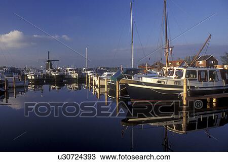 Netherlands, Boats in harbor and windmill reflect in the calm waters of a canal in Lisse. View Large Photo Image Stock Image - Netherlands, Boats in harbor and windmill reflect in the calm waters of a canal in Lisse.. Fotosearch