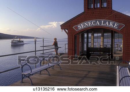 New York, Finger Lakes, Woman watches Captain Bill's Seneca Lake Cruise, the Stroller IV, sightseeing boat from the Watkin's Glen Public Pier on Seneca Lake in Watkins Glen. View Large Photo Image Stock Photograph - New York, Finger Lakes, Woman watches Captain Bill's Seneca Lake Cruise, the Stroller IV, sightseeing boat from the Watkin's Glen Public Pier on Seneca Lake in Watkins Glen. . Fotosearch