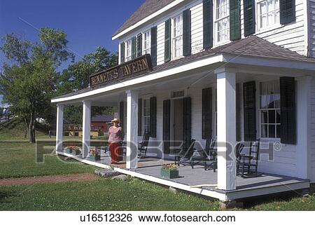 New York, Rome, Woman interpreter stands on the porch of Bonnet's Tavern at the Erie Canal Village. An 1840 restored community., View Large Photo Image Stock Photograph - New York, Rome, Woman interpreter stands on the porch of Bonnet's Tavern at the Erie Canal Village. An 1840 restored community., . Fotosearch