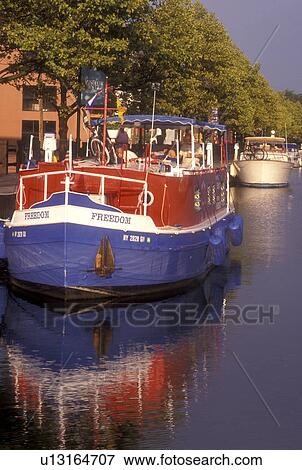 New York, Seneca Falls, Finger Lakes, A red, white and blue cruise line boat along the Cayuga-Seneca Canal reflects in the calm water. View Large Photo Image Stock Photo - New York, Seneca Falls, Finger Lakes, A red, white and blue cruise line boat along the Cayuga-Seneca Canal reflects in the calm water.. Fotosearch