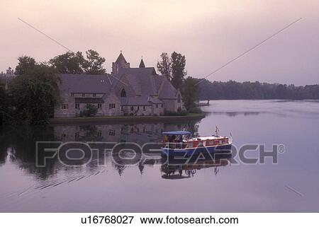 New York, Seneca Falls, Finger Lakes, A cruise line boat travels on the waterway next to Trinity Church. View Large Photo Image Stock Photo - New York, Seneca Falls, Finger Lakes, A cruise line boat travels on the waterway next to Trinity Church. . Fotosearch