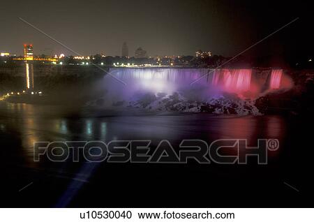Stock Image -  Niagara Falls, New York, The American Falls are illuminated at night (evening) in Niagara Falls in the state of New York . Fotosearch