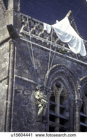 Stock Image -  Normandy, France, Manche, Europe, A figure of the World War II paratrooper hangs from the church tower in Ste Mere Eglise. Sainte-Mere-Eglise was the first French town liberated on D-Day.. Fotosearch