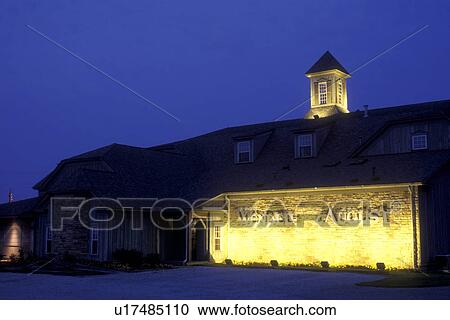 Stock Image -  Ohio, Holmes County, Amish, Lights illuminate the front of The Wendell August Forge in the evening.. Fotosearch