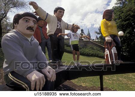 Stock Photography -  Ottawa, Ontario, Canada, Young girl standing and imitating a large sculpture of people in a park next to the Rideau Canal in Ottawa in the Province of Ontario, Canada.. Fotosearch