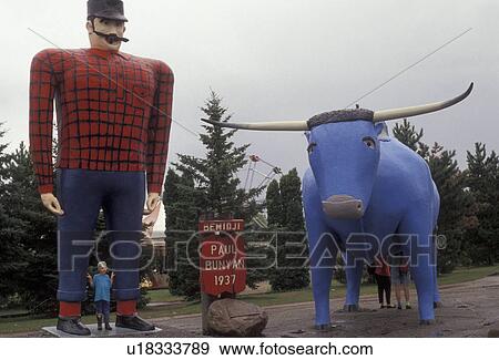 Stock Photo -  Paul Bunyan, Minnesota, Young boy stands posing for a picture in front of giant Paul Bunyan and Babe the Blue Ox Statues in the town of Bemidji in the state of Minnesota . Fotosearch