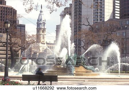 Stock Image -  Philadelphia, Pennsylvania, Fountain at Logan Circle and view of City Hall in downtown Philadelphia, Pennsylvania. The fountain was cast by Alexander Stirling Calder.. Fotosearch