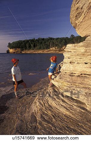 Stock Photo -  Pictured Rocks, hiking, Lake Superior, Upper Peninsula, U. P Michigan, Mother and daughter standing on the edge of the sandstone cliffs on Lake Superior at Pictured Rocks National Lakeshore in Munising in the state of Michigan.. Fotosearch