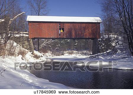 Stock Photo -  red covered bridge, winter, Vermont, A woman stands in the window of The Slaughter House Covered Bridge which crosses over the partially frozen water of the Dog River on a winter day in Northfield Falls in Washington County in the state of Vermont.. Fotosearch