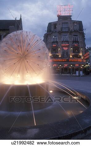 Stock Image -  Reims, Champagne Region, France, Marne, Europe, Fountain and restaurant at the plaza in downtown Reims illuminated at night in France. . Fotosearch