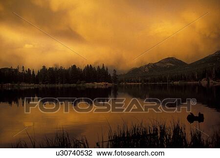 Stock Image -  Rocky Mountain National Park, sunrise, mountains, lake, Colorado, clouds, Rocky Mountains, Reflection of the mountains at [sunset, sunrise] on the calm waters of Sprague Lake in Rocky Mountain National Park.. Fotosearch